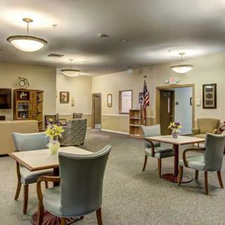A spacious and well-lit lobby area with tables and chairs arranged for meetings or social gatherings.