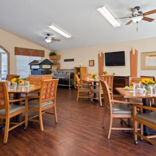 A cozy dining area with wooden floors, tables, chairs, and a television.