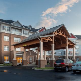 A modern hotel entrance with parked cars and a brick exterior.