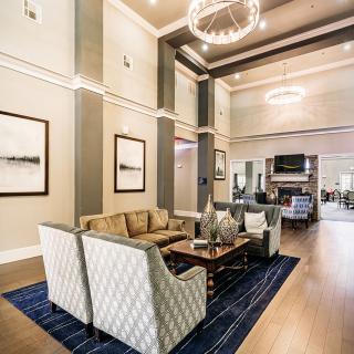 A spacious and elegantly designed living room with modern furniture, high ceilings, and a chandelier.