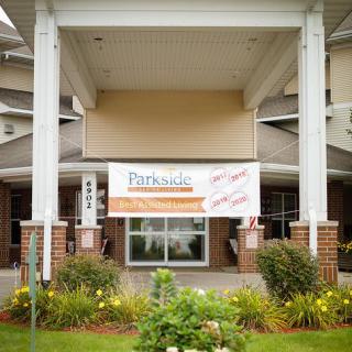 The entrance of a building featuring a banner and landscaped garden.