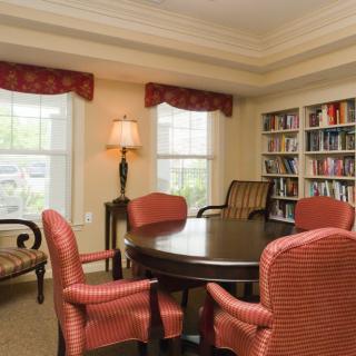A cozy reading room with a round table, armchairs, and bookshelves.