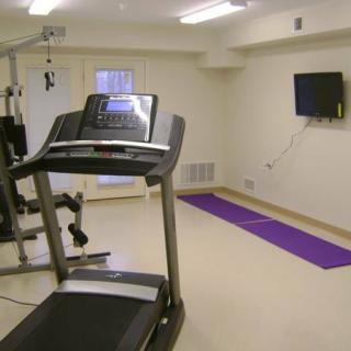 A simple home gym setup with a treadmill and yoga mat.