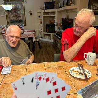 Two elderly men enjoying a card game at the dining table in a cozy kitchen setting.