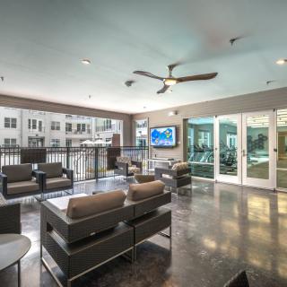 A modern lounge area with comfortable seating, a television, and large windows providing ample natural light.