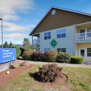 A two-story building with a surrounding landscape, featuring a blue sign and clear sky.