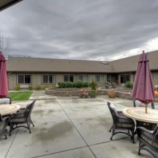 A courtyard with patio furniture and umbrellas under an overcast sky.