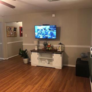 A cozy living room with a mounted television, wooden flooring, and tasteful decor.