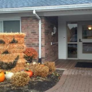 An entrance decorated with pumpkins and hay bales for the autumn season.