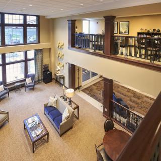 A spacious living room with a loft, featuring large windows and comfortable furniture.