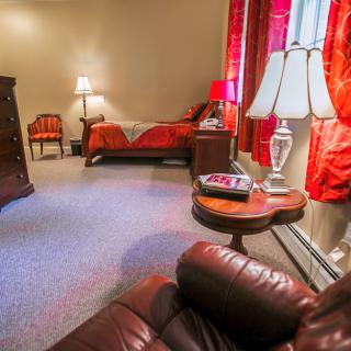 A cozy bedroom with red accents and elegant lighting.