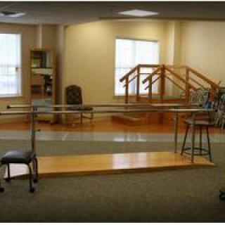 A rehabilitation room equipped with parallel bars and steps for physical therapy exercises.