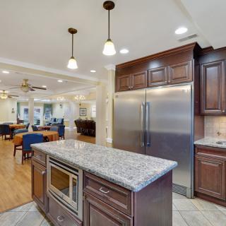 A modern kitchen with a granite countertop island and stainless steel appliances.