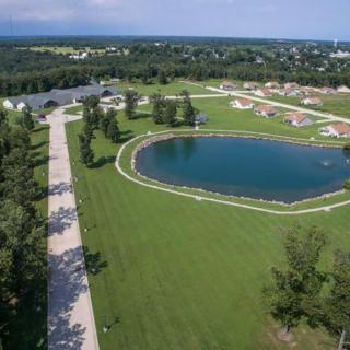 A scenic aerial view of a grassy park featuring a large pond and surrounding residential areas.