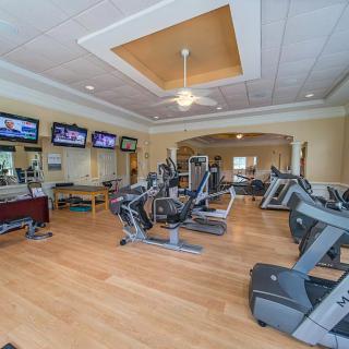 A bright and spacious gym with various exercise machines and treadmills.