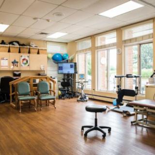 A well-equipped physical therapy room with exercise machines and comfortable seating.