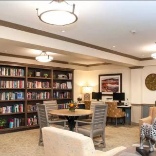 A cozy library space with bookshelves, seating, and computers for reading and study.