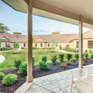 A view of a building's courtyard with neatly landscaped garden and covered patio seating.
