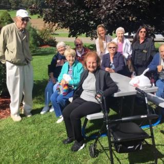 A group of seniors enjoying a sunny day at the park, gathered around a picnic table.