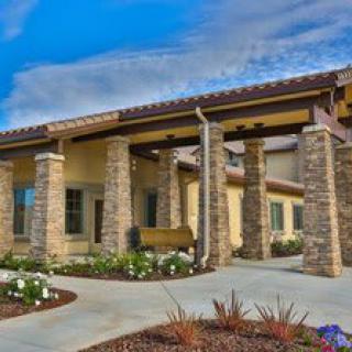 A modern building entrance with stone columns and landscaped surroundings under a clear blue sky.