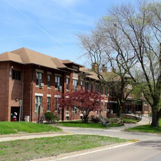 A brick building surrounded by trees and greenery, showcasing a peaceful outdoor environment in spring.