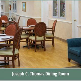 An empty dining room with neatly arranged tables and chairs, labeled 'Joseph C. Thomas Dining Room'.