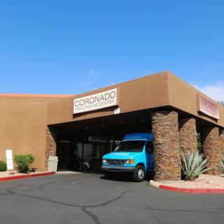 A commercial building with a van parked in front under a sunny blue sky.