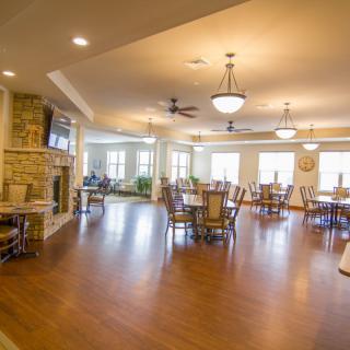 A spacious and well-lit dining room with wooden floors and elegant furniture.