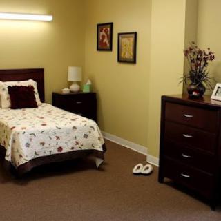 A cozy bedroom featuring a neatly made bed, a dresser, and decorative wall art.