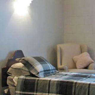 A cozy bedroom with a neatly made bed and a comfortable armchair.