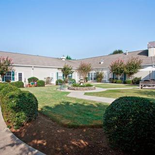 A well-maintained courtyard with manicured bushes and a central garden area in front of a single-story building.