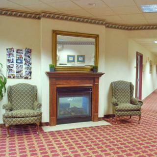 A cozy hallway with a fireplace, two patterned chairs, and a large mirror above the mantel.