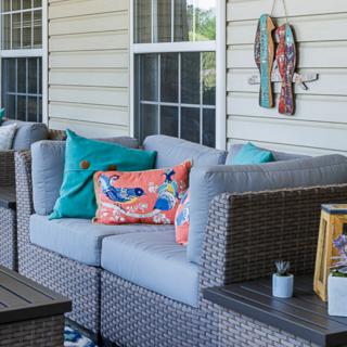A cozy patio setting with rattan outdoor furniture featuring colorful cushions and decorative wall art.