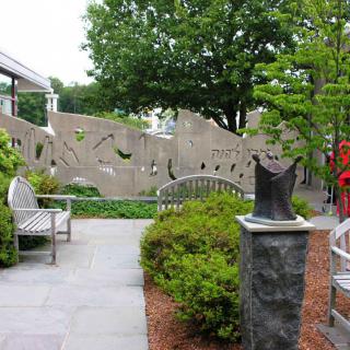 A peaceful garden setting with benches, sculptures, and lush greenery.