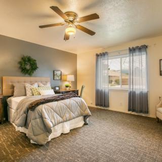 A cozy bedroom featuring a comfortable bed, ceiling fan, and a bright window with curtains.