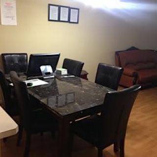A home office setup on a dining table with a sofa in the background.