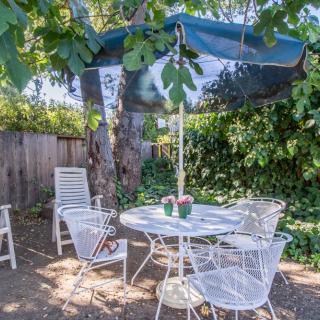 A peaceful garden patio with white metal furniture and a shaded umbrella.