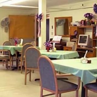 A cozy dining area with tables, chairs, and a computer setup.