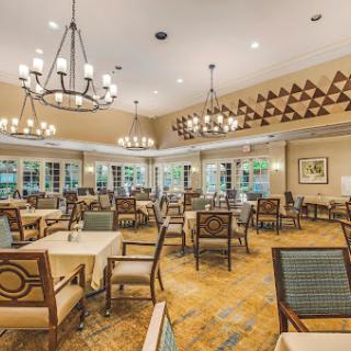 A spacious and elegantly designed dining room featuring tables and chairs under beautiful chandeliers.