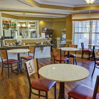 A cozy cafe interior with several tables and chairs arranged in a warm, inviting setting.
