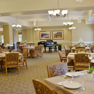 A spacious dining room with elegantly set tables and a grand piano.