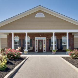 A welcoming entrance to a residential building with landscaped surroundings and classic column architecture.