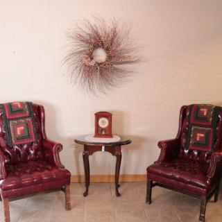 A cozy seating area featuring two vintage burgundy armchairs and a decorative wall piece.