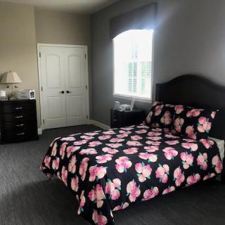 A cozy bedroom featuring a bed with floral bedding, a dresser, and a window.