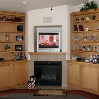 A cozy living room featuring built-in wooden bookshelves, a fireplace, and a mounted television.