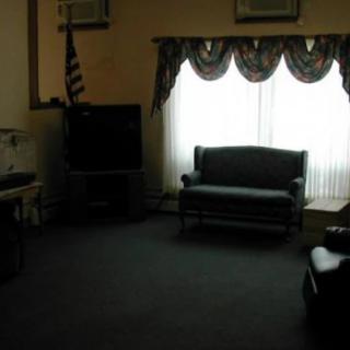 A dimly lit living room with a sofa, television, and curtains.