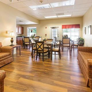 A cozy living and dining area with wooden flooring, furnished with sofas, tables, and chairs.
