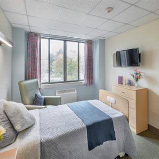 A cozy and well-lit bedroom featuring a comfortable bed, modern furniture, and a large window.