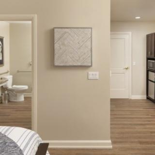 A modern interior view featuring a bedroom, bathroom, and kitchen area with hardwood flooring.