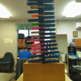 A colorful vertical structure made of stacked items, set in an office environment.